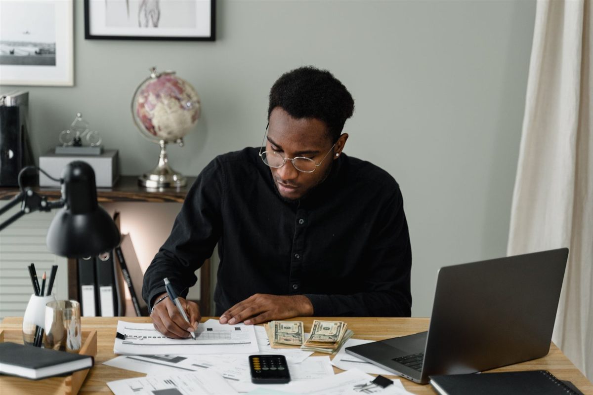 A man at his desk reviewing bills and writing a debt repayment plan