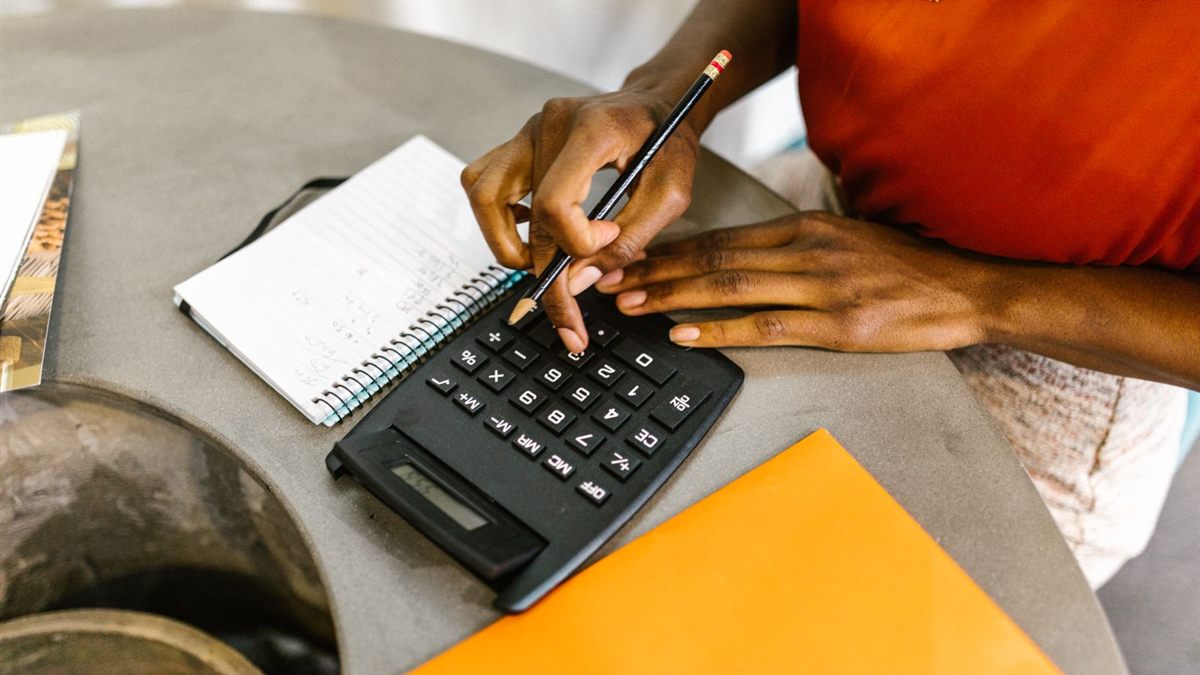 A woman planning her monthly budget with a calculator, pencil and notebook