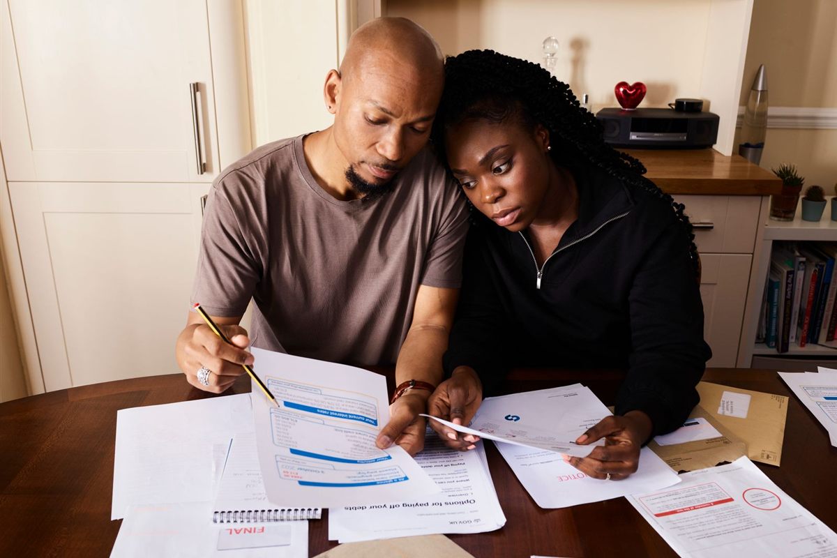 A couple sitting close together at their kitchen table going through bills and documents