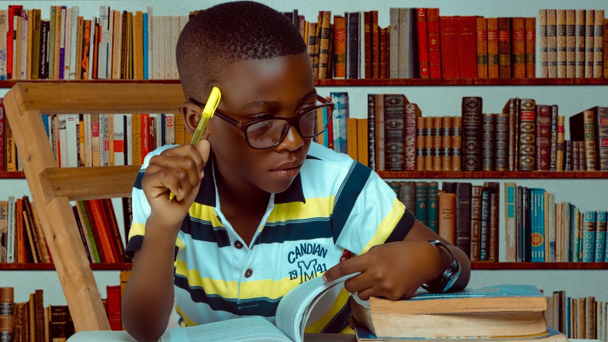 Boy reading and taking notes at a desk in a library