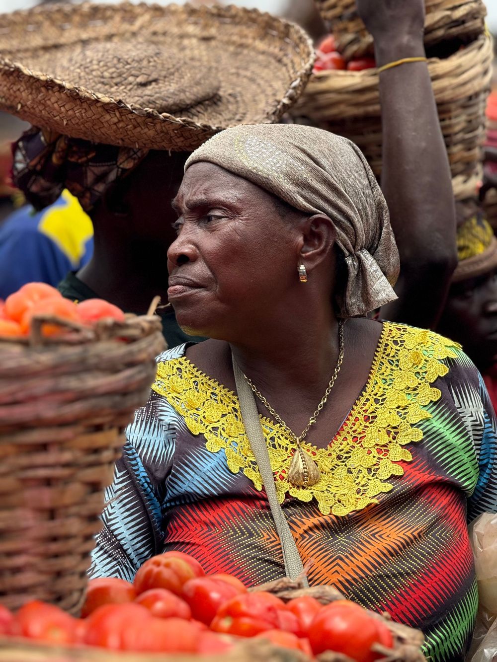 An older woman selling tomatoes at a busy market