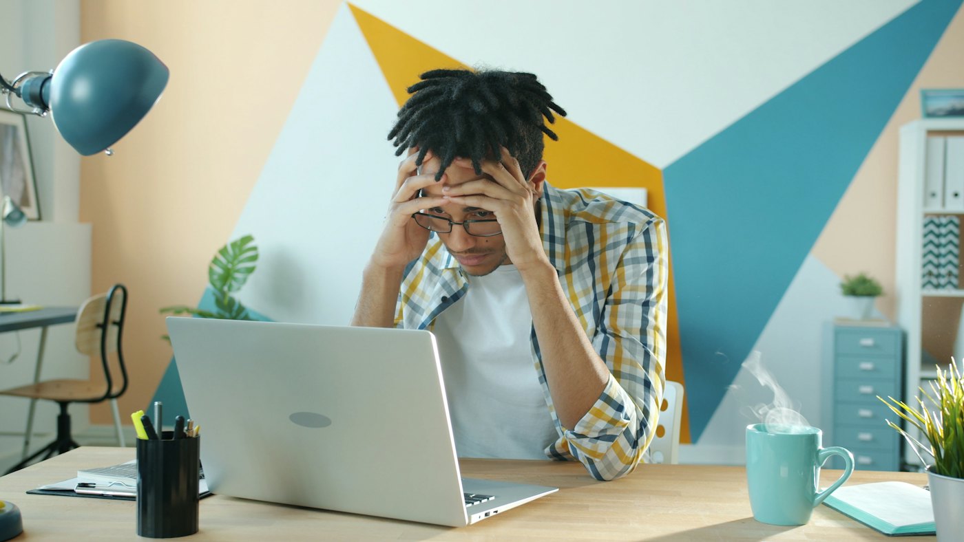 Man at his desk holding his head, showing signs of work stress